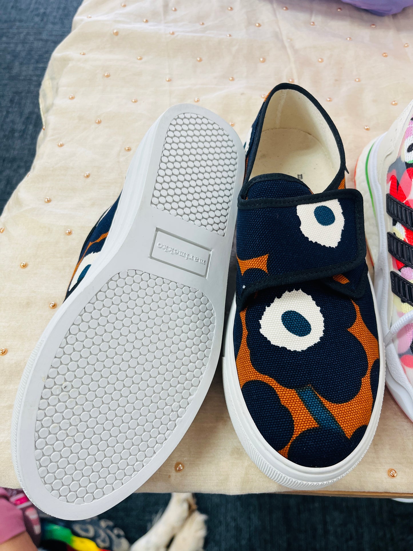 Pair of slip-on shoes with a colorful pattern on a textured surface