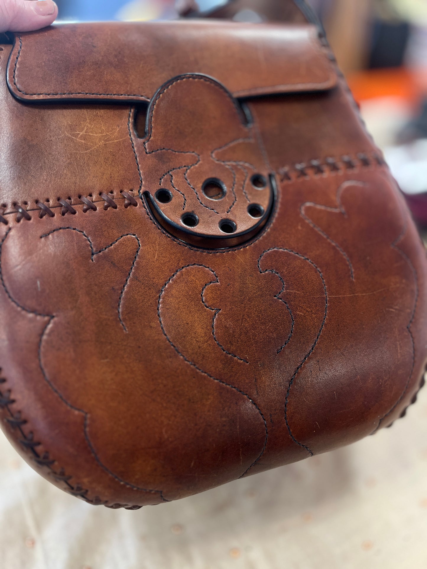 Brown leather bag with intricate designs and a decorative clasp.