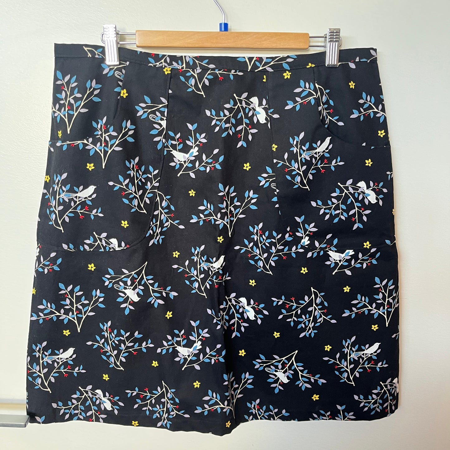 Black shorts with floral and bird pattern on a hanger