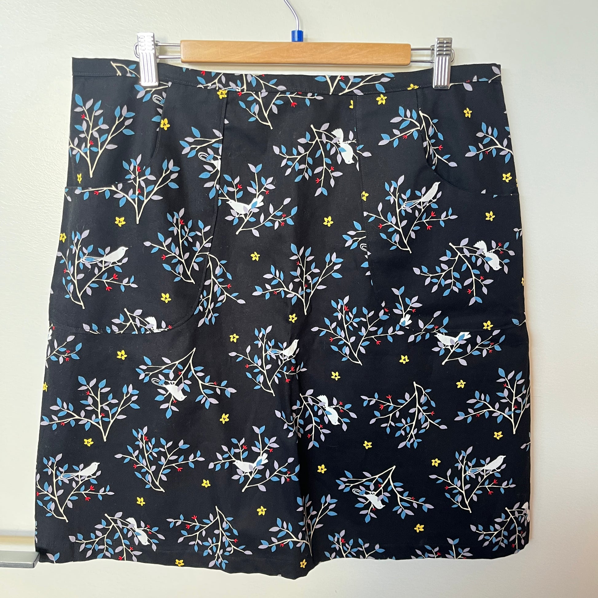Black shorts with floral and bird pattern on a hanger