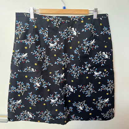 Black shorts with floral and bird pattern on a hanger