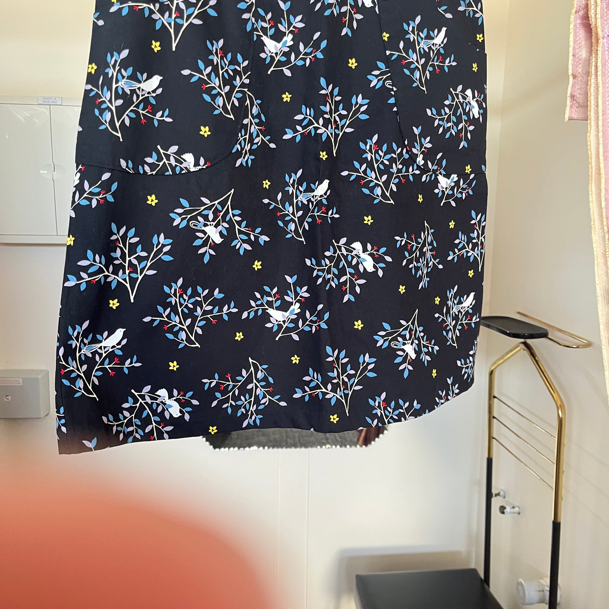 Black skirt with floral and bird pattern hanging on a rack