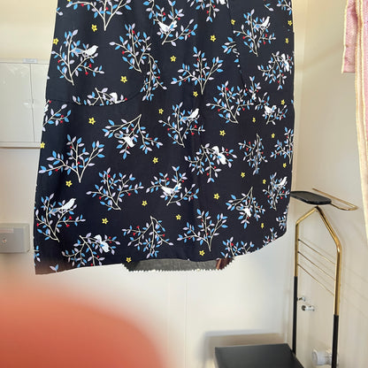 Black skirt with floral and bird pattern hanging on a rack