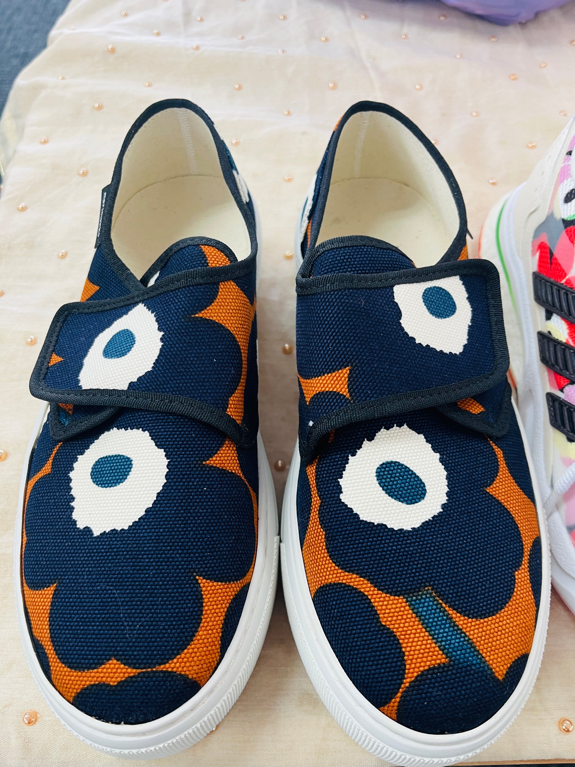 Pair of navy blue and orange patterned shoes with white soles