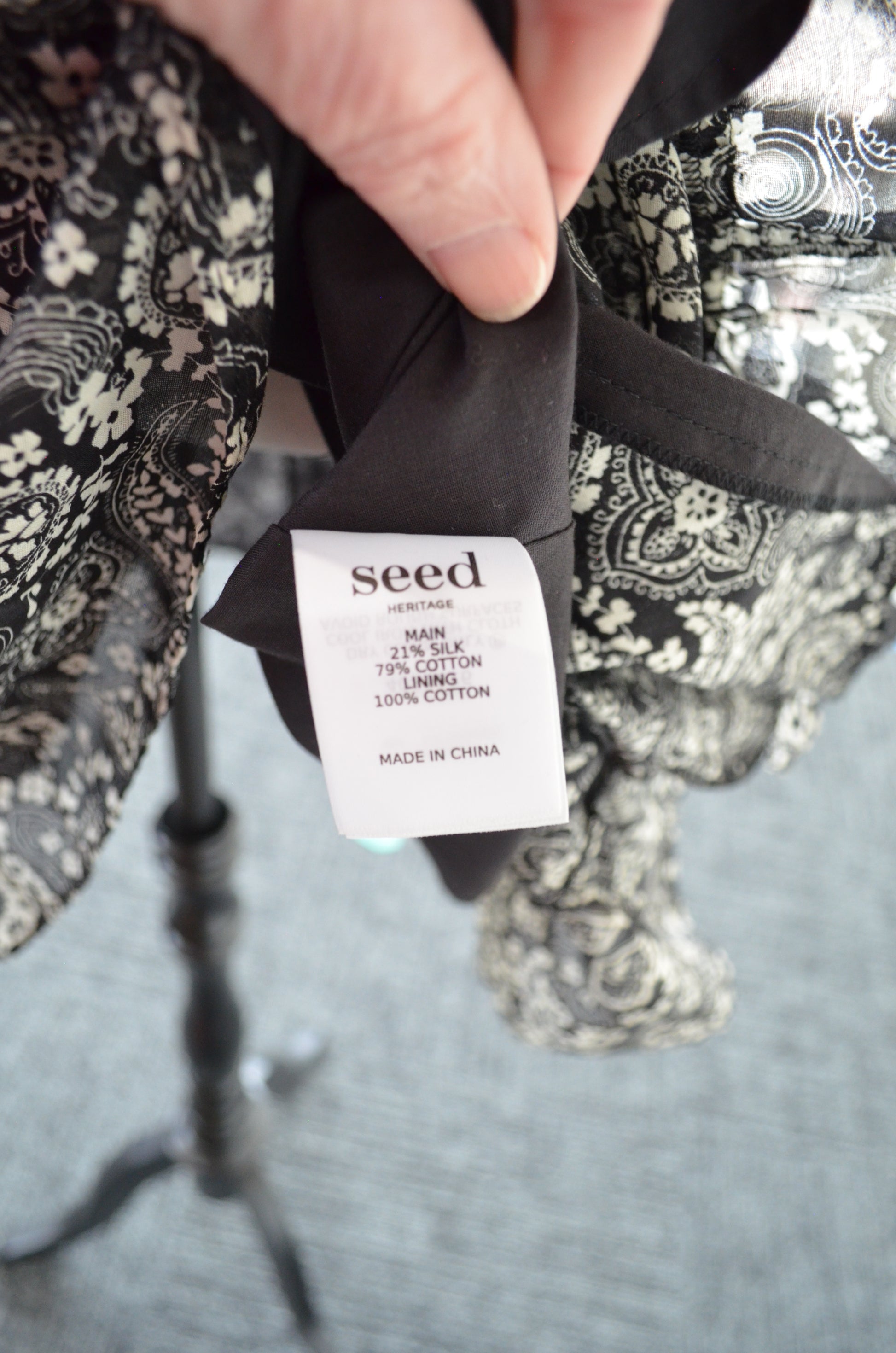 Close-up of a hand holding a garment with a 'seed' label