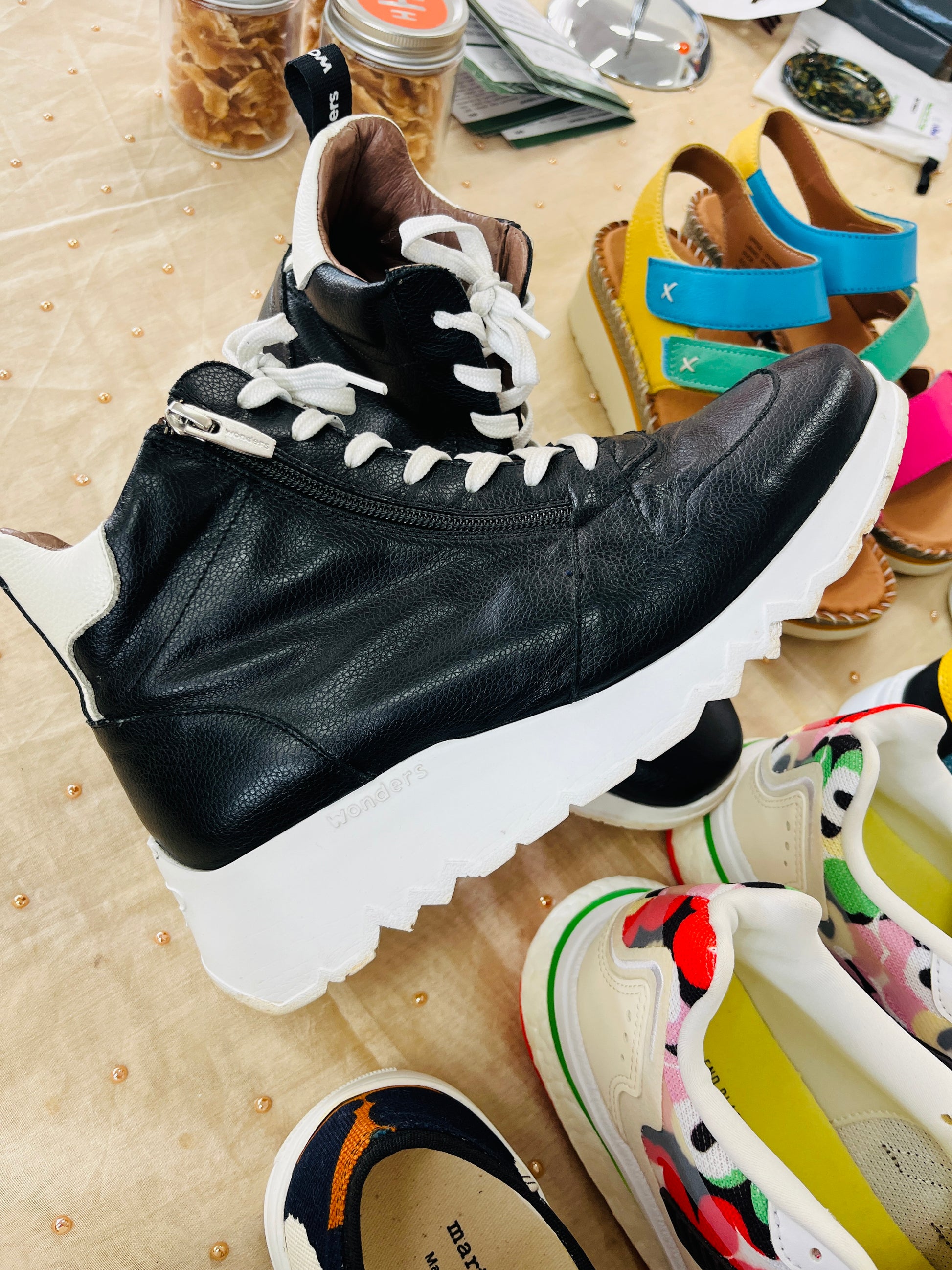 Black leather boot with white sole on a wooden surface