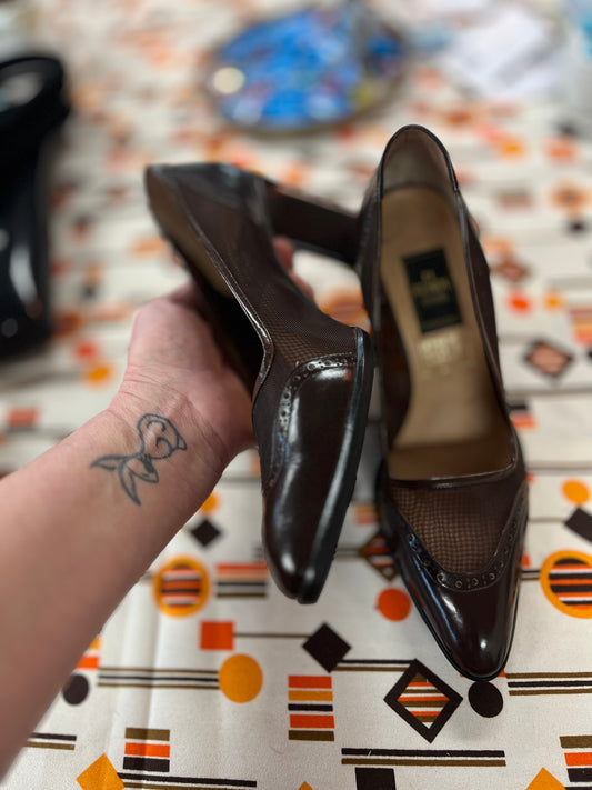 Pair of black shoes held by a hand