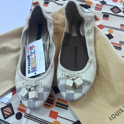 Pair of Louis Vuitton shoes with a visible tag on a patterned surface