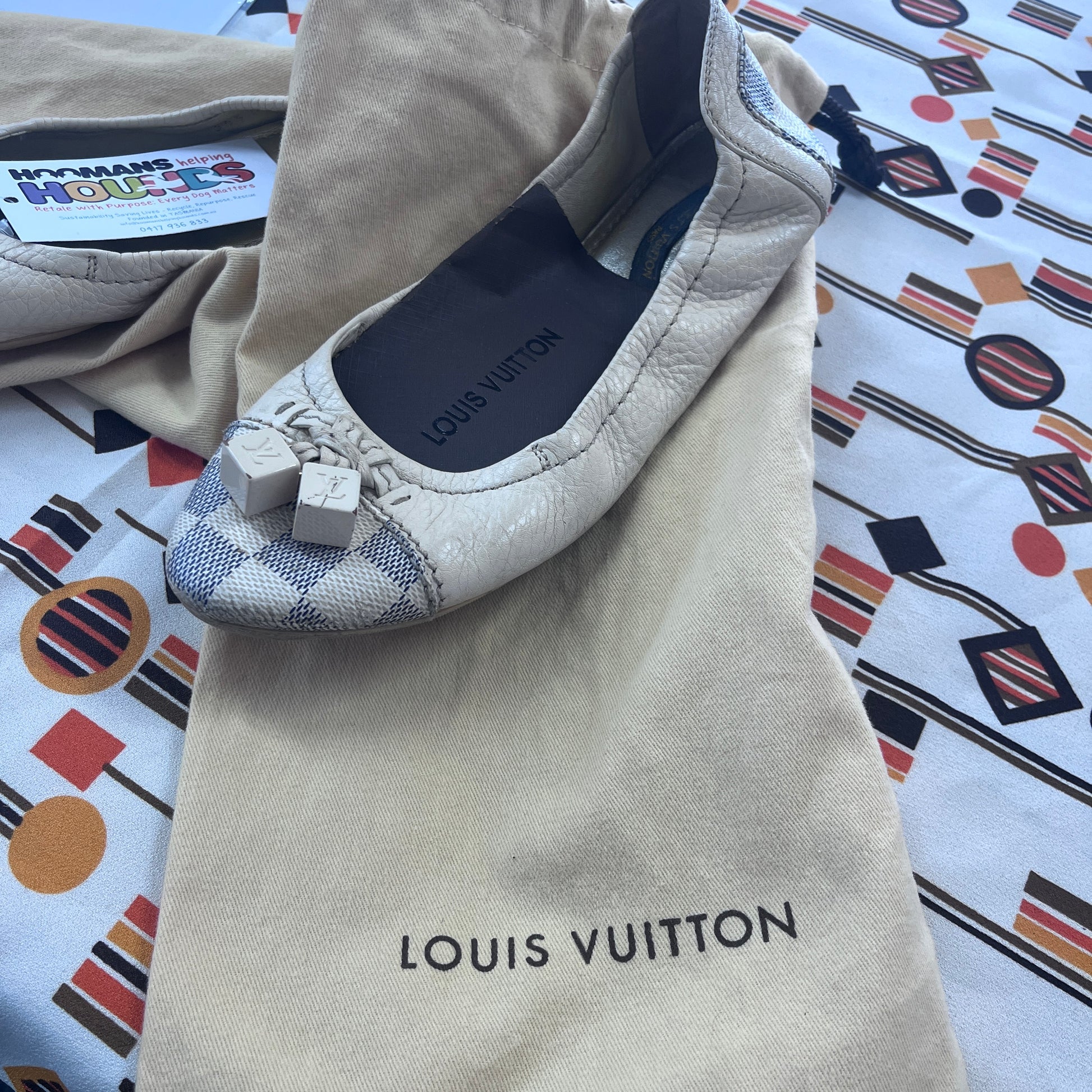 Louis Vuitton flat shoe on a branded pouch with a colorful patterned background