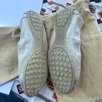 Pair of Louis Vuitton shoes with textured soles on a patterned fabric background