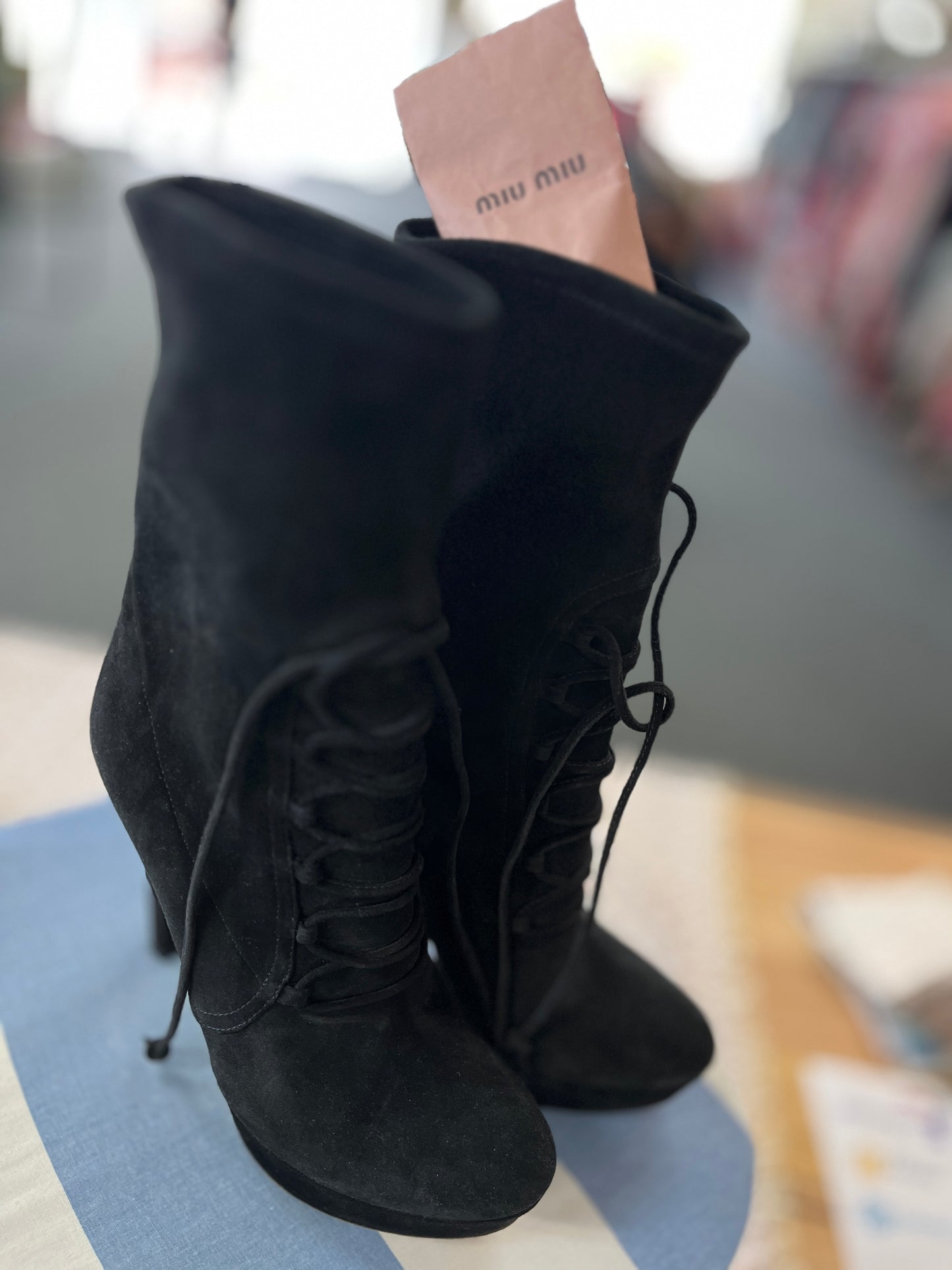 Black suede boots with a brand tag on a blurred background