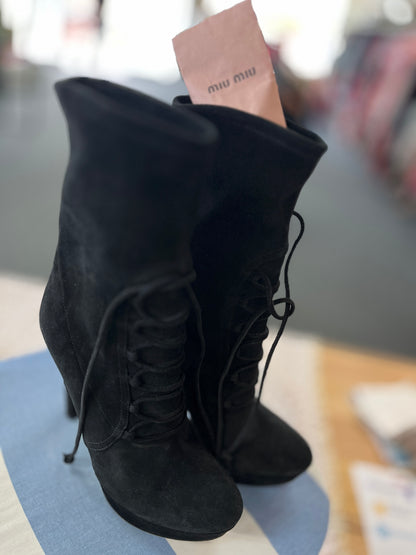 Black suede boots with a brand tag on a blurred background