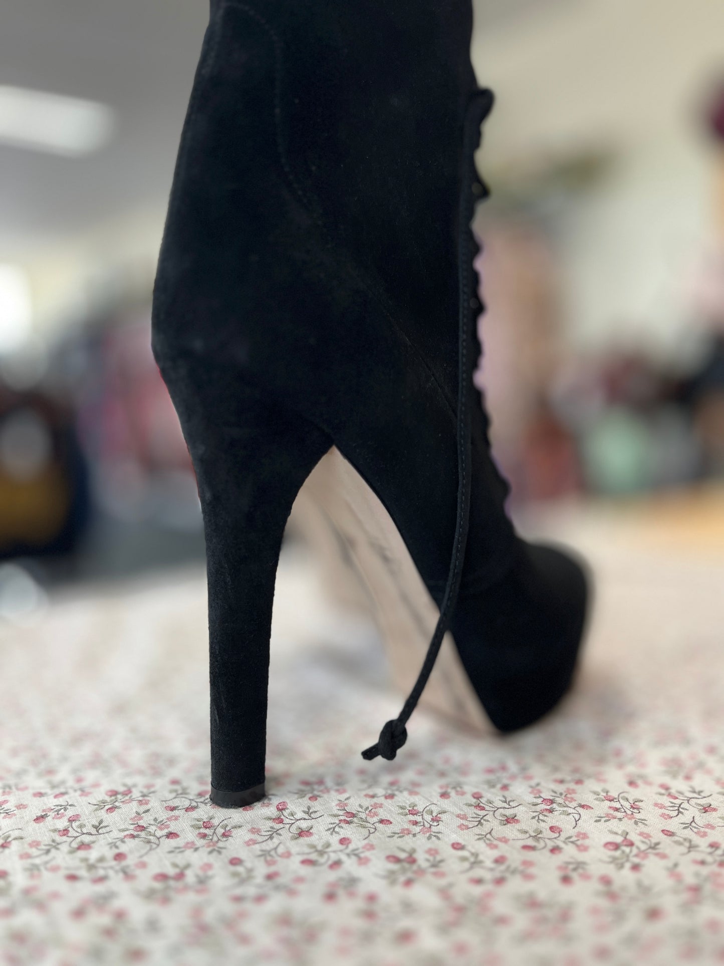Black high-heeled boot on a floral-patterned surface