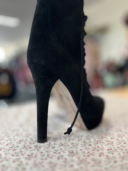 Black high-heeled boot on a floral-patterned surface